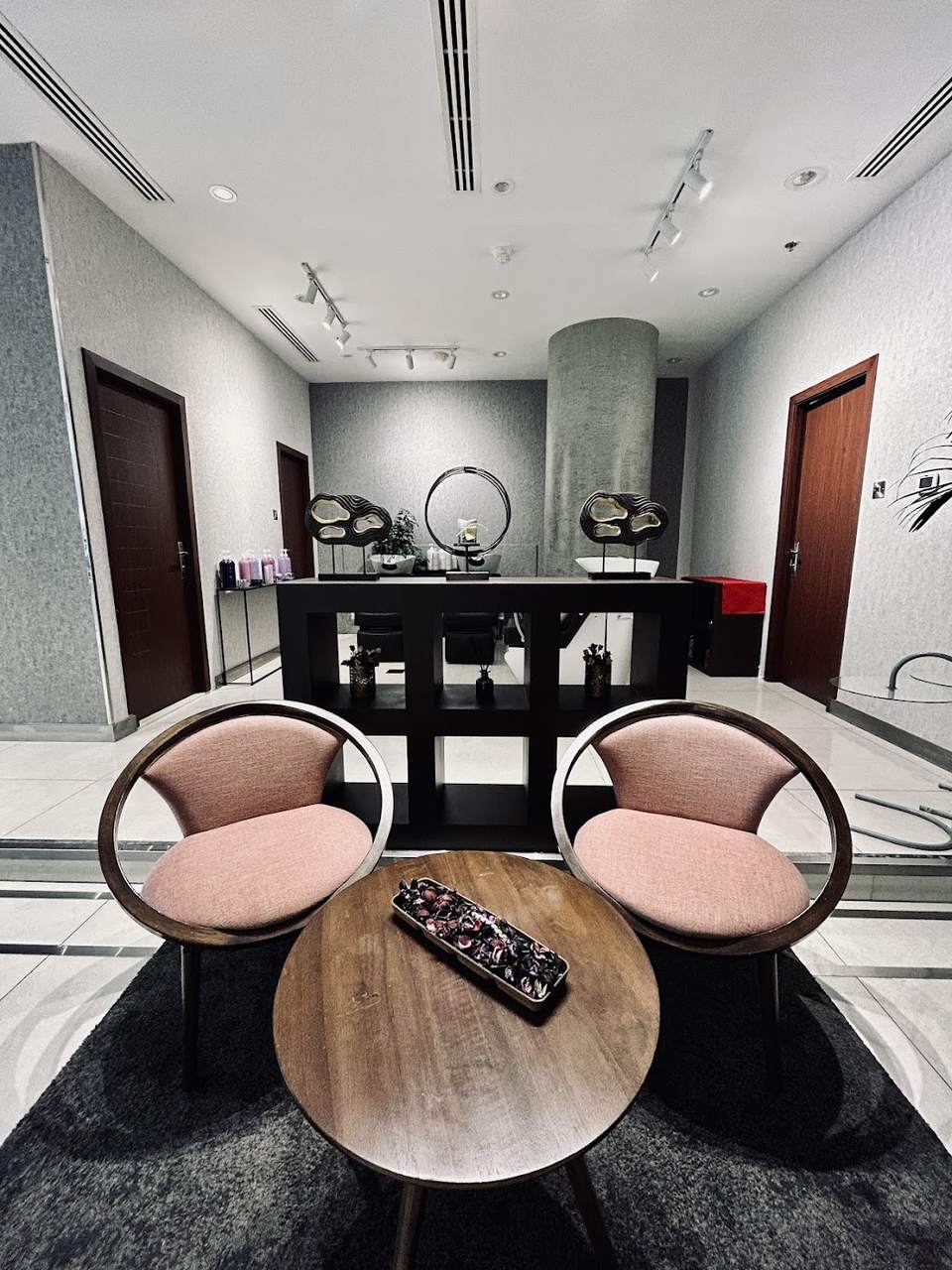 Two blush velvet chairs and a walnut side piece in the Venere by Ann lounge